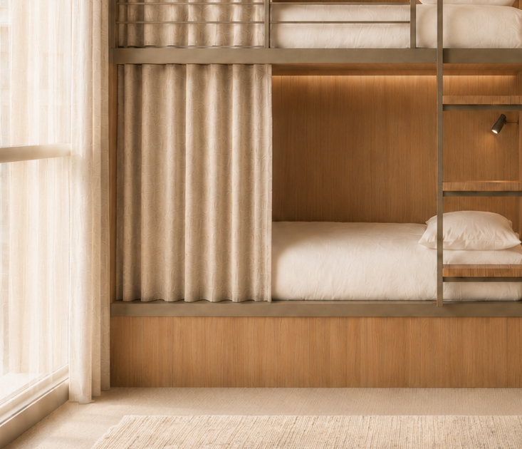 Bunk bed nook with a beige curtain divider, light wood panels, and white bedding in a warm-toned room.