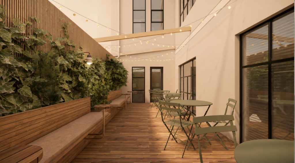 Outdoor courtyard with a wooden deck, green folding tables and chairs, string lights, and a ivy-covered wall with planters along the side.